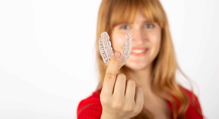 Beautiful smiling young woman with aligner.