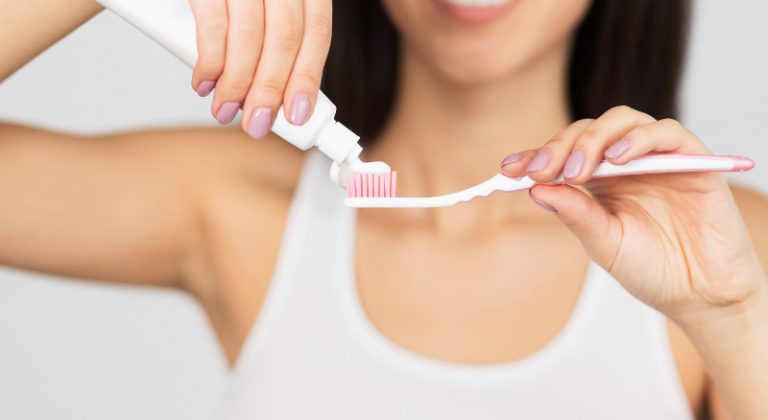 unrecognizable-woman-putting-toothpaste-on-KALQJGR